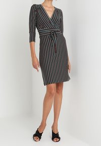 Zavinovací šaty s černým podkladem a barevnými vertikálními pruhy, ¾ rukávy, páskem v pase a výstřihem do V. Měkká, elastická látka.