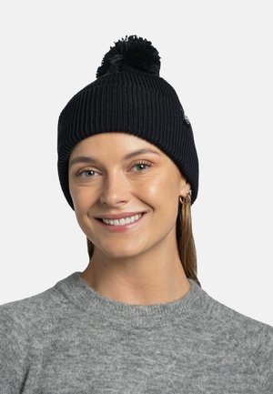 Gorro de punto negro con textura acanalada y un pompón en la parte superior. Acompañado de un suéter gris, que muestra un aspecto casual y cálido.