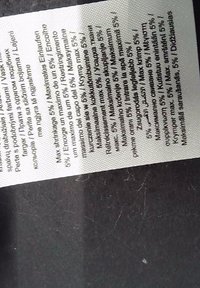 Étiquette d'entretien des vêtements indiquant les instructions de composition du tissu en plusieurs langues sur une étiquette blanche sur fond sombre.