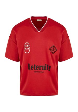 Jersey rojo de manga corta con escote en V, que presenta logotipos y texto impresos en negro, hecho de tela suave. Los detalles incluyen ribetes blancos.