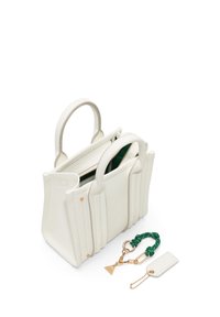 Vit texturerad läderhandväska med två rundade handtag, prydd med en grön accentnyckelring och en dekorativ guldkedja.