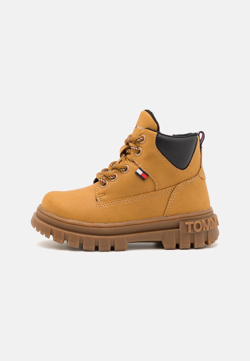 Stivale alla caviglia in suede marrone con dettagli neri, design con lacci e suola in gomma robusta. Presenta il logo Tommy sul lato.