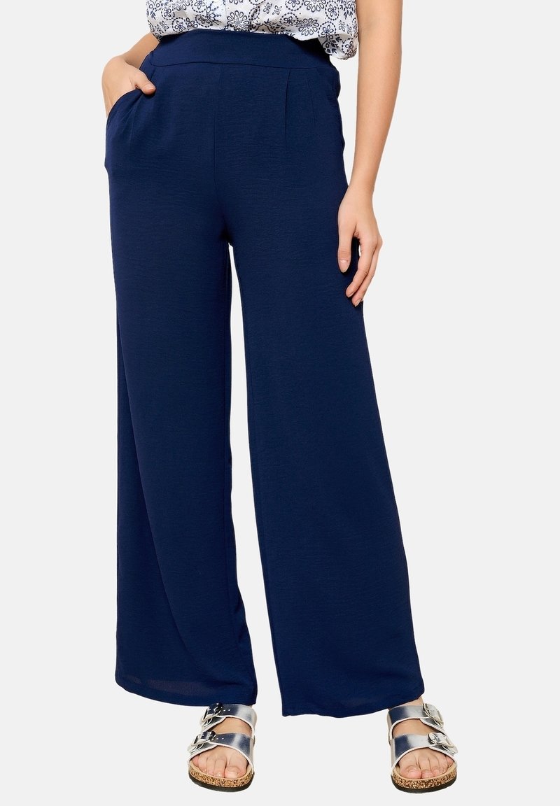 Námořnické široké kalhoty vyrobené z lehkého materiálu s hladkým povrchem. Obsahují přední kapsy a plochý pas. Stříbrné sandály dotvářejí vzhled.