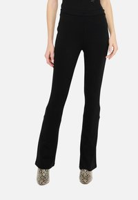 Zwarte flare-broeken met een soepele elastische tailleband. Gemaakt van rekbaar materiaal, met een slim fit bij de heupen en dijen.
