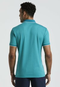 Polo shirt teal avec un motif texturé, à manches courtes et une bordure de col contrastante. La vue arrière met en évidence la coupe et les détails de design.