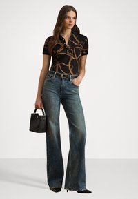 Polo shirt nero con motivo a catena marrone, jeans blu a vita alta e svasati, borsa nera, tacchi a punta neri.