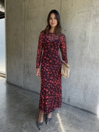 Langermet, svart kjole med rød blomsterdesign, tettsittende rundt livet. Kombinert med en beige veske og sko med dyreprint. Betongbakgrunn.