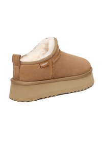 Brauner Wildleder-Slipper mit dicker Gummisohle und weißem Plüschfutter, mit kleinem "EVERAU" Stoffetikett an der Seite.