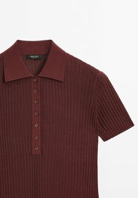 Burgundy randig piké med kort krage, med en knappad frontplacket och korta ärmar. Tillverkad av ett strukturerat stickat material.