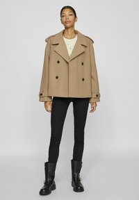 Brun ylleblandad peacoat med dubbelknäppning, stora svarta knappar, axelremmar, kombinerad med svarta skinny jeans och svarta ankelskor.