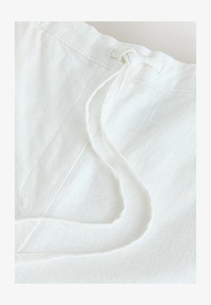 Hvid linnedstof med en tekstureret overflade. Har en snøre lukning med løkkeender, der viser et blødt, luftigt udseende.