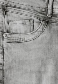 Jeans de denim de color gris claro con un bolsillo frontal que incluye un pequeño bolsillo para monedas, costuras visibles y un diseño de cintura clásico.