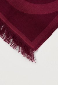 Bordeaux vævet stof med subtilt mønster og frynser kan ses på en ensfarvet hvid baggrund.