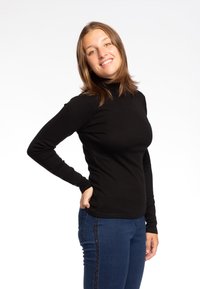 Maglione a maniche lunghe nero con collo alto, aderente al corpo, abbinato a jeans blu con un accento laterale di glitter scuro. Design semplice e contemporaneo.