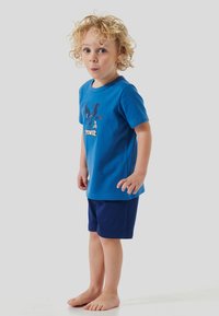 Kurzarmiges blaues T-Shirt mit grafischem Design und Text, kombiniert mit navyblauen Shorts. Merkmale sind eine lockere Passform und eine glatte Baumwolltextur.