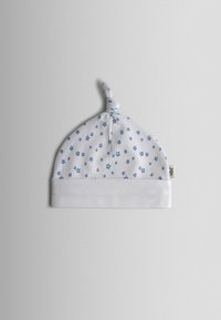 Biela detská čiapka s modrým vzorom hviezdičiek, so zloženým lemom, uzlíkom na vrchu a malou textilnou nálepkou na boku.