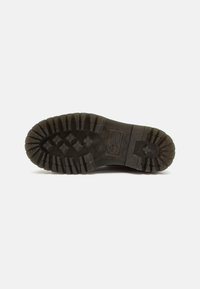Suela de bota con profundas y robustas crampones, fabricada en goma negra. Presenta un talón reforzado y un diseño de agarre para mayor tracción.