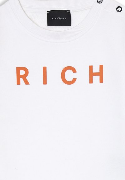 Felpa bianca con la parola "RICH" in grassetto lettere arancioni. Include dettagli in hardware nero sulle spalle. Morbido tessuto di cotone.