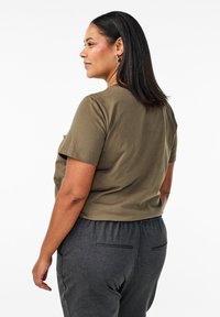 T-shirt a maniche corte color verde oliva con vestibilità comoda, abbinato a pantaloni grigio carboncino con elastico in vita e tasche laterali.