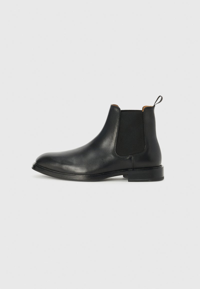 Svart läder Chelsea-boots med en strömlinjeformad design, elastiska sidopaneler, en slinga baktill och en platt sula. Slät yta.