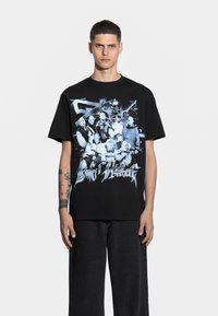 Czarny t-shirt z bawełny z niebieskim nadrukiem graficznym przedstawiającym wiele postaci oraz stylizowanym tekstem z przodu. Krój jest luźny, z krótkimi rękawami.