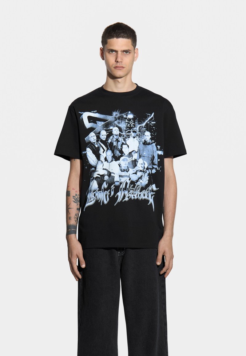 Czarny t-shirt z bawełny z niebieskim nadrukiem graficznym przedstawiającym wiele postaci oraz stylizowanym tekstem z przodu. Krój jest luźny, z krótkimi rękawami.