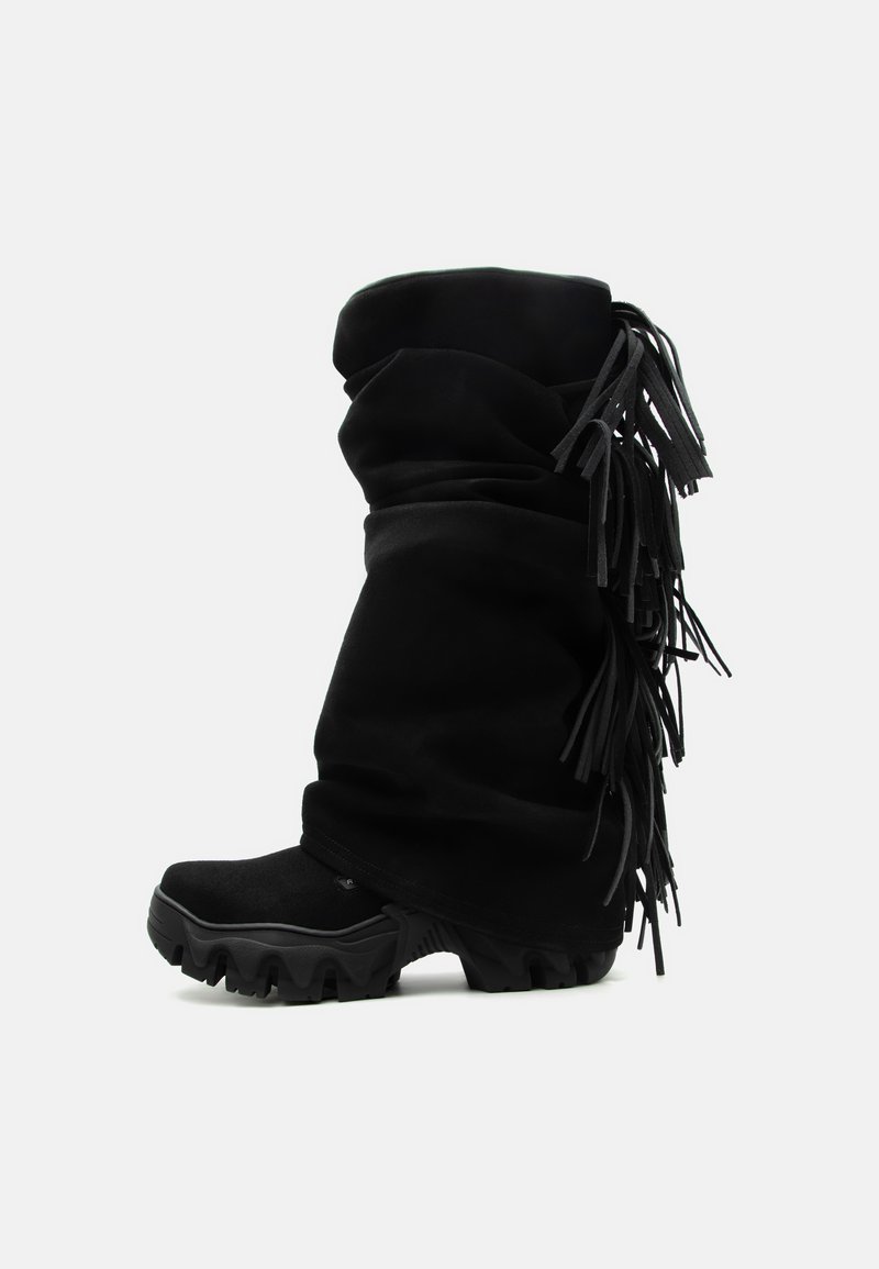 Μαύκη χαλαρή μπότες μέχρι τη μέση της γάμπας με χοντρή σόλα και κρόσσια που κρέμονται από την πίσω πλευρά.