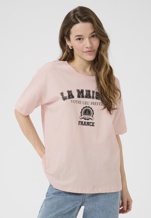 T-shirt en coton rose clair avec une coupe décontractée, présentant un texte imprimé noir et un design graphique. Manches courtes et encolure arrondie.