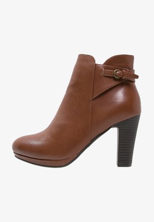 Brown leather ankle boot with a curved silhouette, side buckle accent, and a stacked high heel. Smooth texture and rounded toe design.