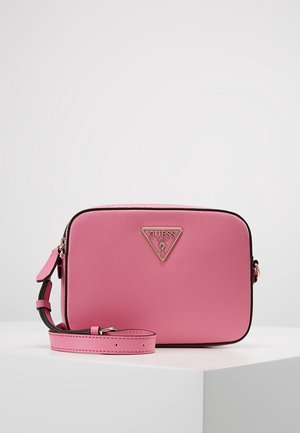 Rectangular pink Guess crossbody bag with adjustable strap and triangular metal logo plaque on front, placed on white surface.