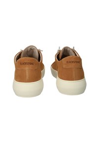 Zapatillas de ante marrón con una suela blanca redondeada, que cuentan con un panel trasero cosido etiquetado "BLACKSTONE" y elementos de diseño minimalistas.