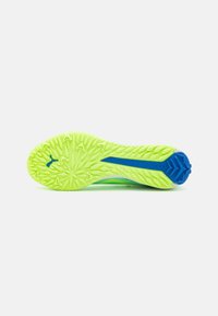 Suela de zapatilla deportiva en verde y azul con un patrón texturizado, material de goma y una forma de suela distintiva con picos para tracción.