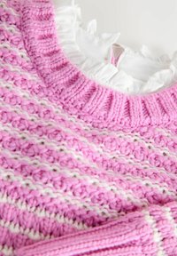 Maglione spesso a righe rosa e bianche con colletto a coste e dettagli in tessuto bianco a volant sotto.