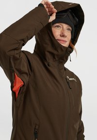 Bruine waterdichte jas met een ritssluiting aan de voorkant, verstelbare capuchon en een mesh accent aan de zijkant. Heeft een minimalistisch design met logo.