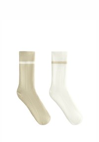 Twee paar geribde sokken: één in beige met een witte streep, en één in wit met een beige streep. Beide hebben een gestructureerde zool.