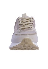 Zapatilla deportiva beige con material de malla y cuero, puntera redondeada, diseño de cordones y suela de goma con patrón.