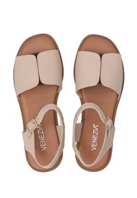 Beige leren sandalen met een vierkante neus, twee brede banden en een verstelbare enkelband, met een bruine binnenzool en een lichtbruine buitenzool.