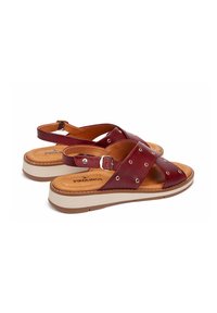 Sandalias de cuero burdeos con anchas correas cruzadas, tachuelas plateadas y cierre de hebilla ajustable. Plantilla acolchada sobre una suela de plataforma blanca.