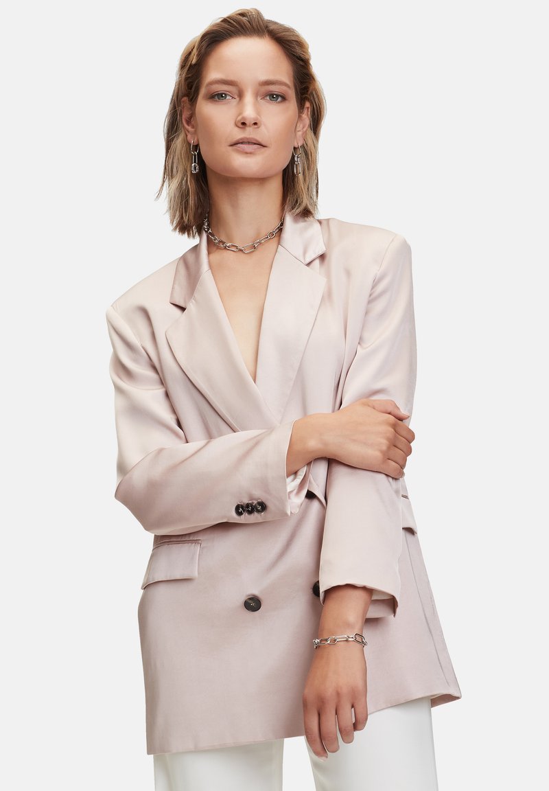 Blush-satiner Blazer mit doppelter Knopfleiste, eingekerbten Revers, Fronttaschen und Knopfdetails. Abgeschlossen mit taillierten Ärmeln.