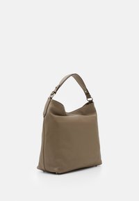 Borsa a tracolla in morbida pelle color beige con una sola tracolla regolabile, cima arrotondata e superficie testurizzata. Design minimalista senza hardware visibile.
