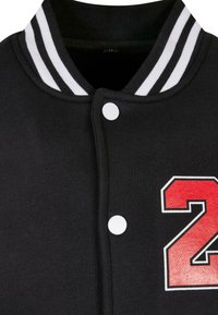 Black varsity jacket with white striped collar, featuring a large red number "2" on the front, and white snap buttons for closure.