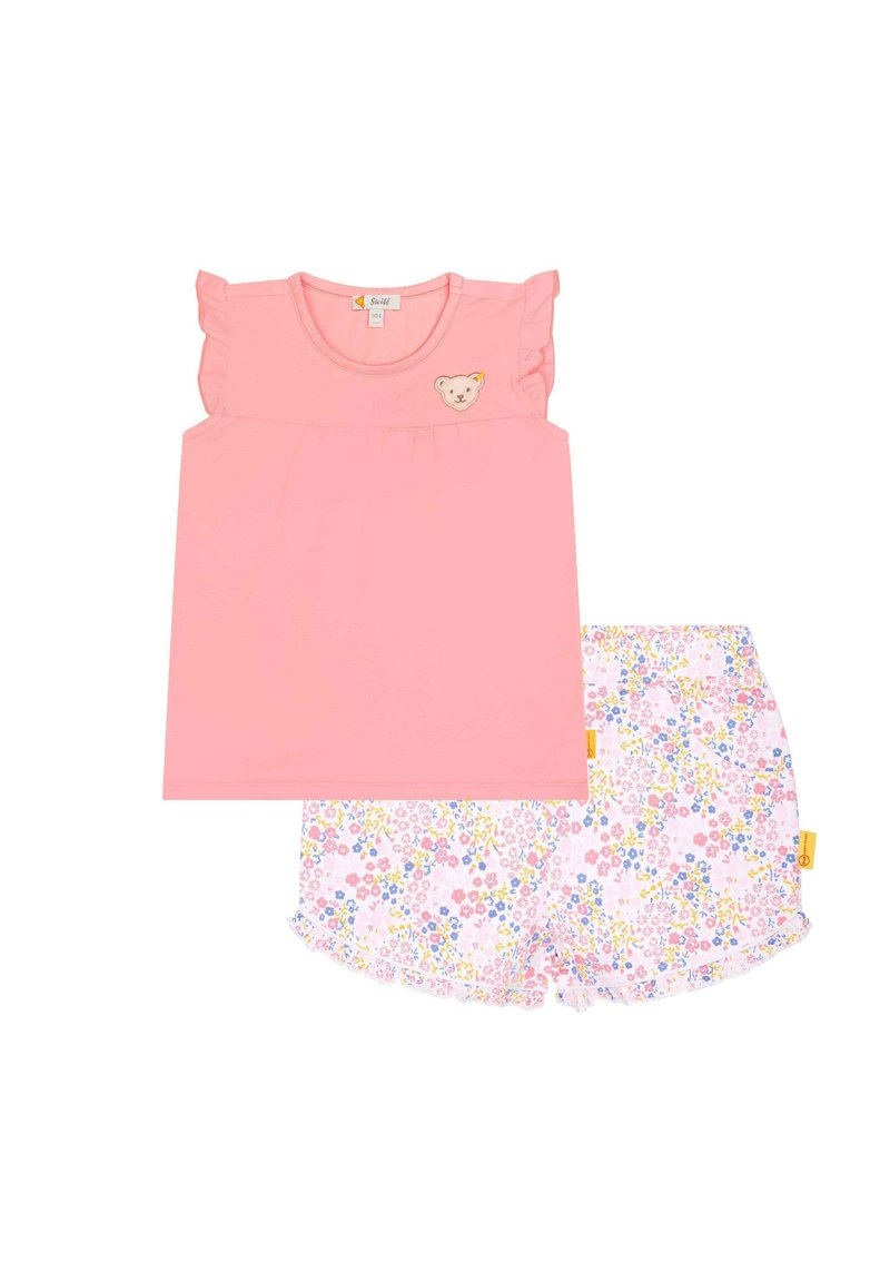 Rosa Oberteil mit Rüschensäumen und Bären-Patch, kombiniert mit weißen Shorts, die ein florales Muster in Pink, Gelb und Blau aufweisen.