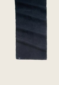Bufanda negra hecha de un tejido suave, con una textura sutil. Los bordes están ligeramente deshilachados. Etiqueta de la marca pequeña en una esquina.