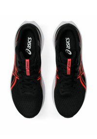 Scarpe da ginnastica nere con parte superiore in mesh, con accenti rossi e suole bianche. Include un logo sulla linguetta e sul lato.