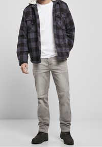 Svart och grå rutigt flanelljacka med en vit faux shearling-krage, bärs över en vit t-shirt, matchad med ljusgrå jeans och svarta stövlar.