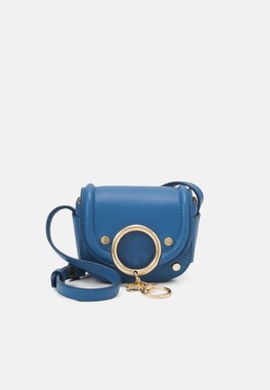 Petit sac bandoulière en cuir bleu avec un anneau doré et un pendentif en détail sur le rabat avant, une sangle ajustable et des bords arrondis.