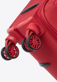 Rode koffer met een textiele buitenkant, vier rode en zwarte wielen en zwarte accenten. Het ontwerp benadrukt wendbaarheid en duurzaamheid.