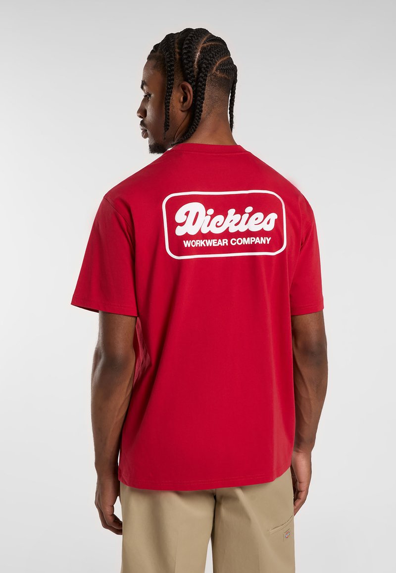 Camiseta de algodón roja con una etiqueta de logo blanca "Dickies WORKWEAR COMPANY" en la parte de atrás. Diseño de mangas cortas y cuello redondo.