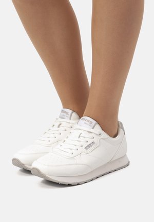 Zapatillas deportivas blancas de material sintético, con un upper texturizado, lengüeta acolchada y sutiles acentos grises en el talón y el logotipo.