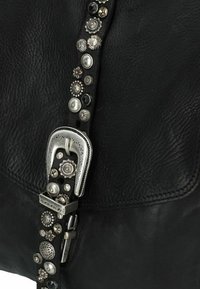 Borsa in pelle nera con una fibbia argentata e dettagli decorativi a borchie lungo la tracolla, con una superficie strutturata e cuciture pulite.